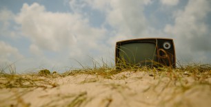 Op deze foto staat een ouderwetse televisie op een duin