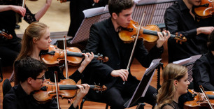ingezoomd op enkele violisten in concertkleding tijdens concert